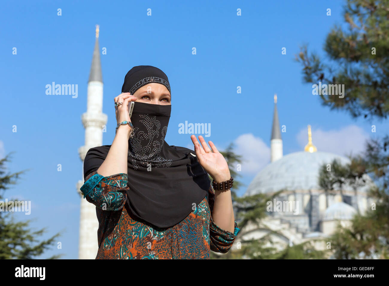 Ritratto di bella donna araba nel tradizionale abbigliamento musulmano parlando al telefono gesticolando Medio Oriente paesaggio urbano wi Foto Stock