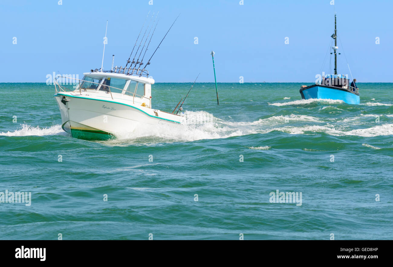 Barche da pesca in mare provenienti verso l'estuario del fiume. Foto Stock