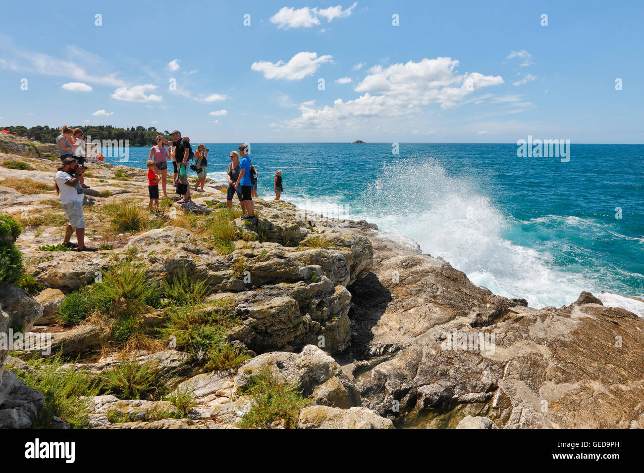 Il turista a godere nel guardare e fotografare onde sulla spiaggia di Rovigno città vecchia Foto Stock