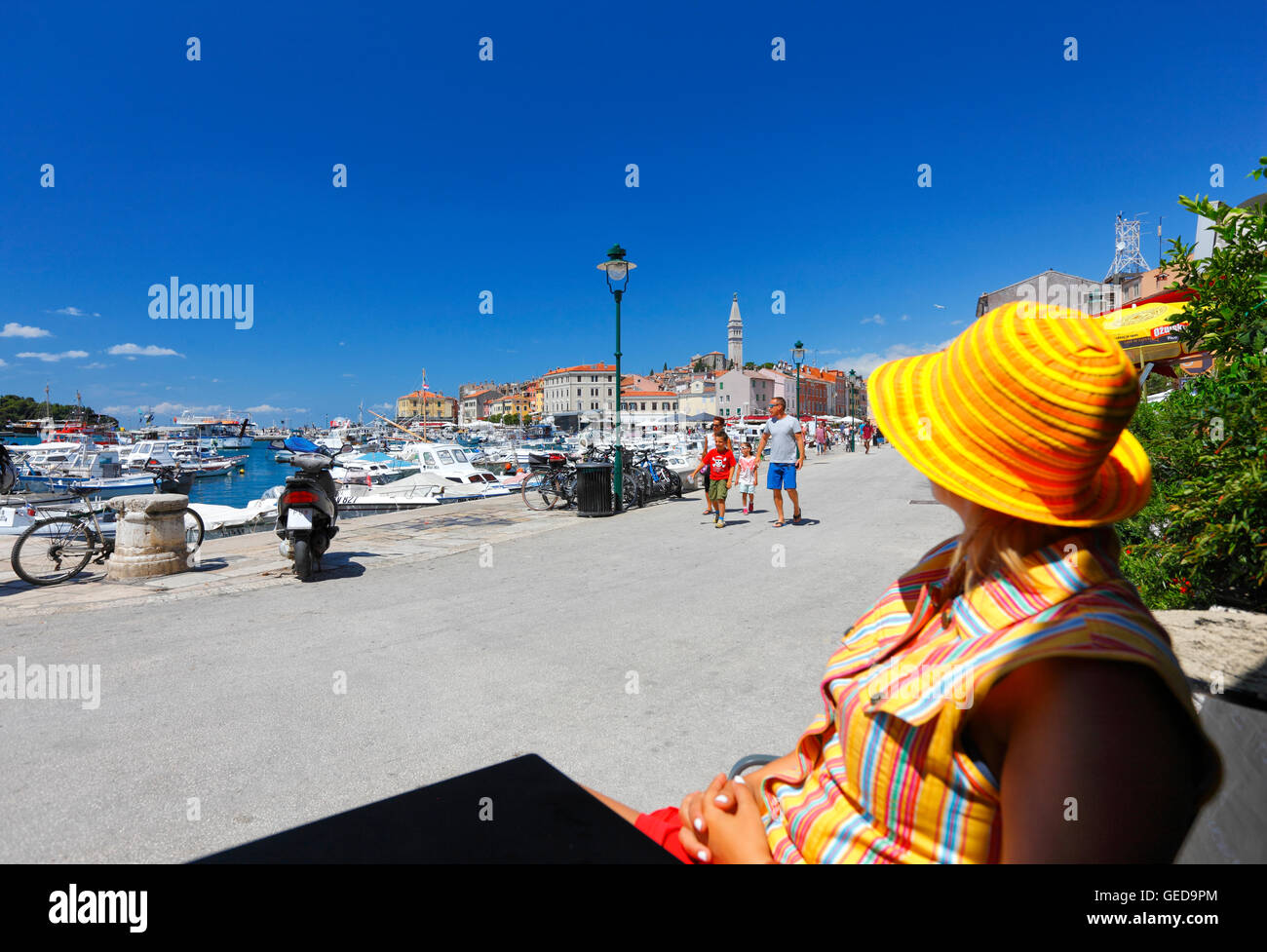 Donna con cappello colorato guardando la città vecchia di Rovigno dal caffe bar Foto Stock