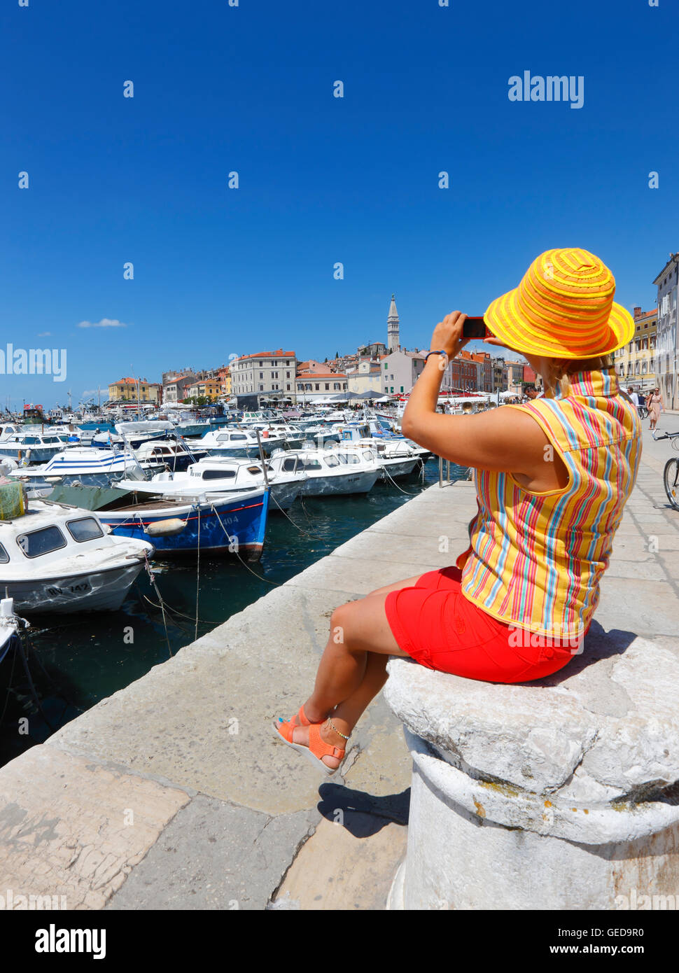 Donna con cappello colorato di scattare le foto della città vecchia di Rovigno da Foto Stock