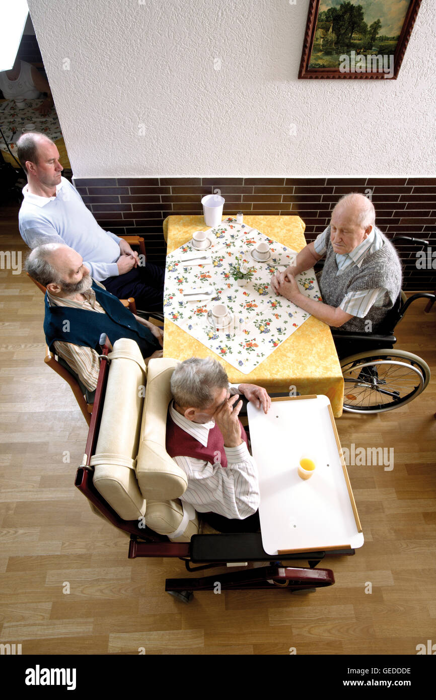 Residenti seduti nella sala da pranzo di una casa di cura Foto Stock