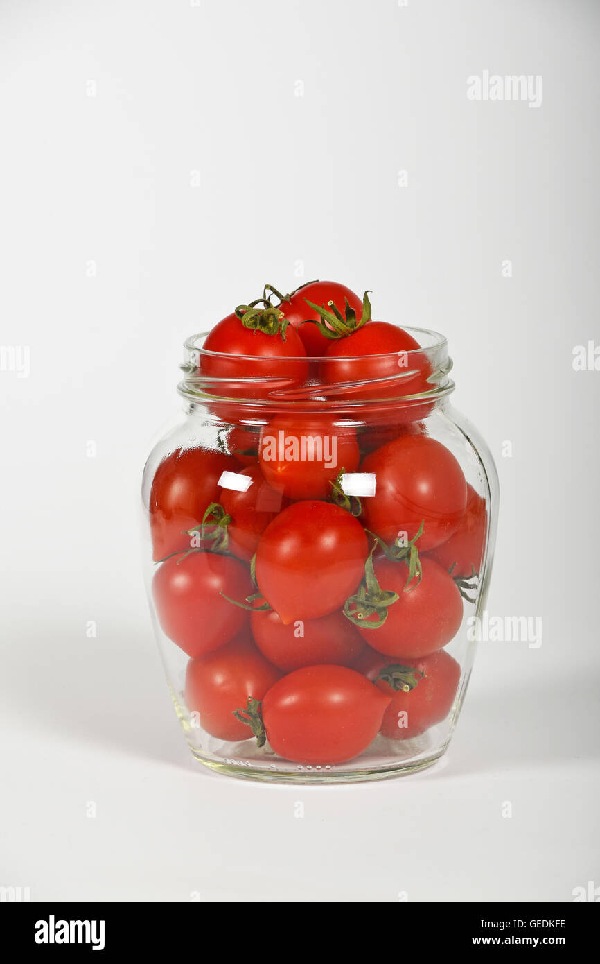 Il vasetto di vetro pieno di rossi pomodori ciliegini pronta per la marinatura per la conservazione su sfondo bianco, vista laterale Foto Stock