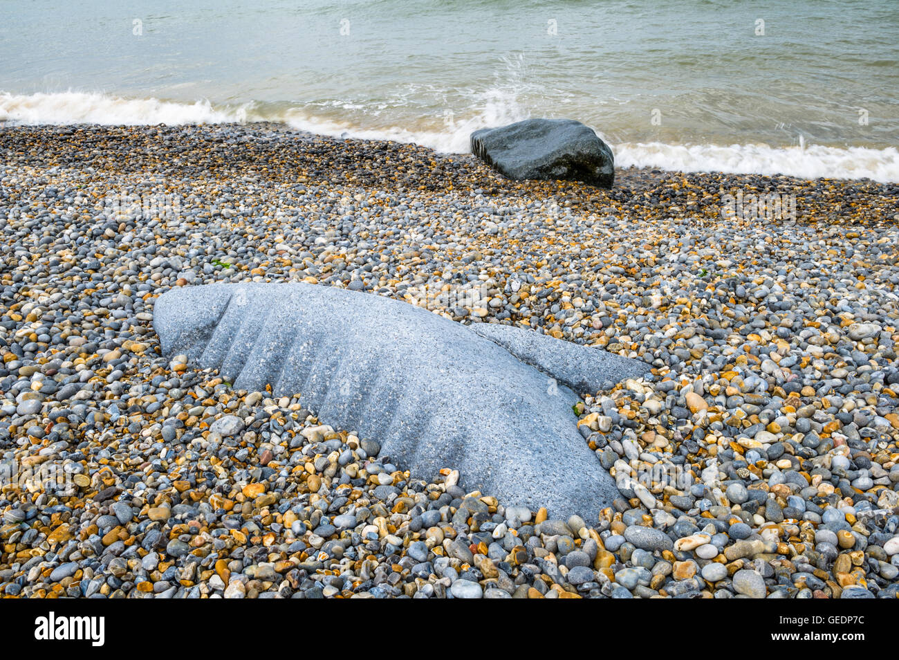 Roccia tagliata in forma di una balena o delfino spiaggiata sulla riva di ghiaia a Sheringham, Norfolk, Inghilterra, Regno Unito Foto Stock