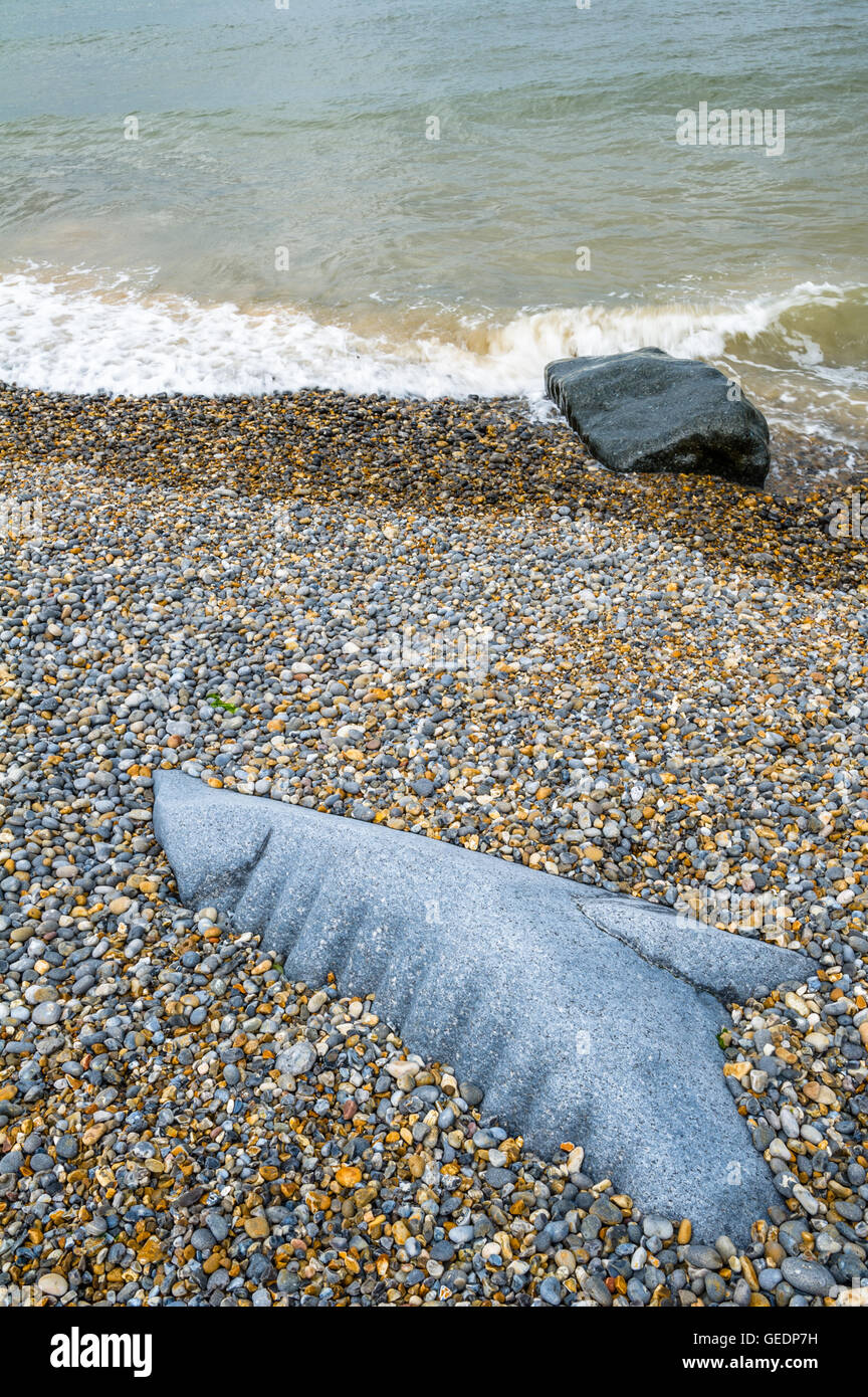 Roccia tagliata in forma di una balena o delfino spiaggiata sulla riva di ghiaia a Sheringham, Norfolk, Inghilterra, Regno Unito Foto Stock