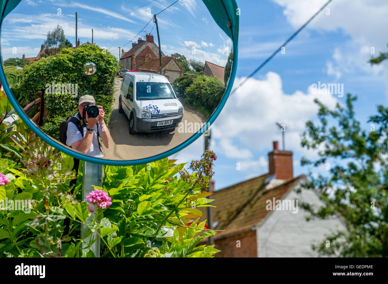 Fotografo prendendo un selfy da una strada specchio rotondo di un tipico villaggio di Norfolk lane. Foto Stock