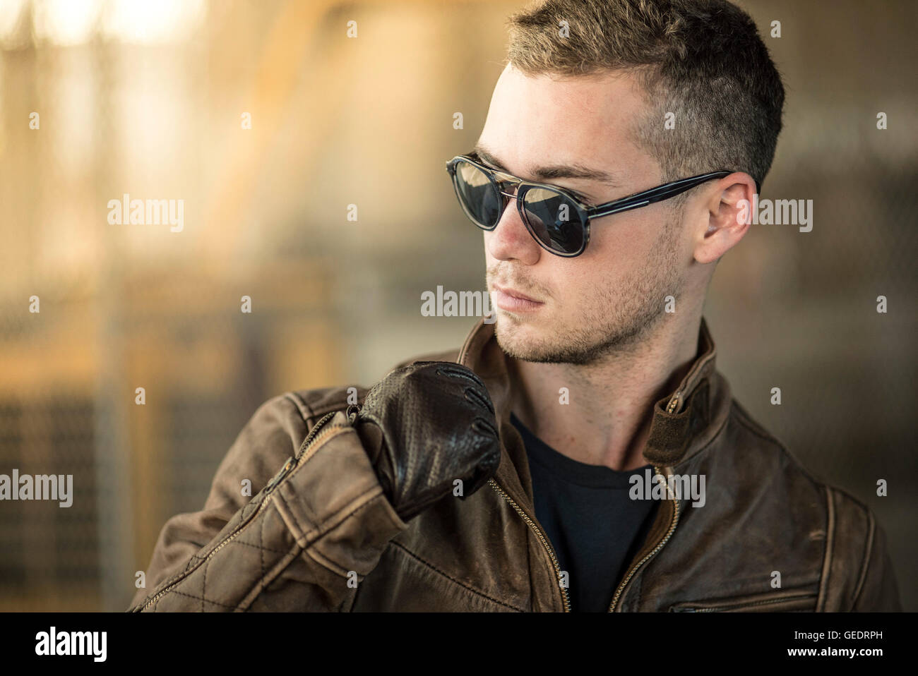 Ritratto di giovane uomo adulto che indossa gli occhiali da sole e giacca di pelle Foto Stock
