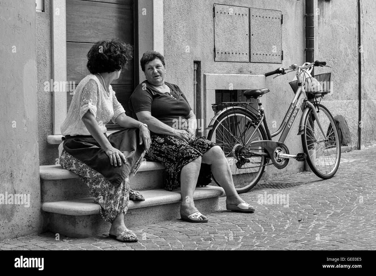 Due donne siedono su una chat a domicilio, Via Trento, Bogliaco di Gargnano, Italia Foto Stock