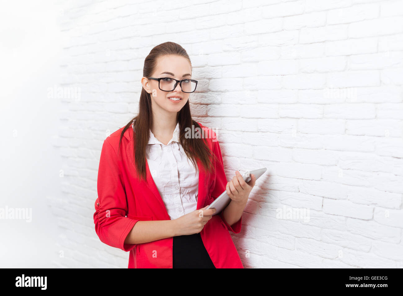 Imprenditrice utilizzare computer tablet indossare giacca rossa bicchieri sorriso Foto Stock