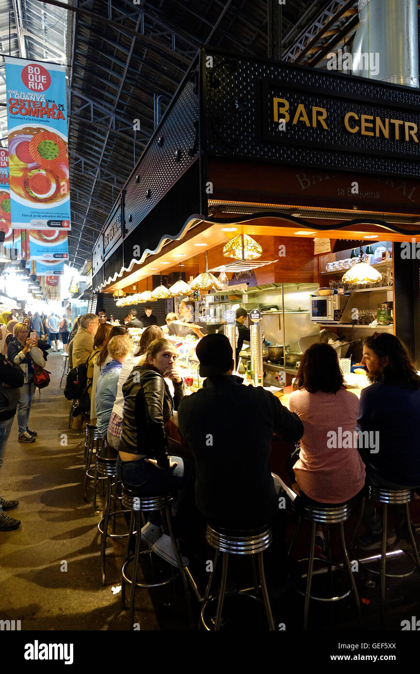 Persone sedersi in un bar per il pranzo o per un drink nel mercato La Boqueria a Barcellona, Spagna. Foto Stock