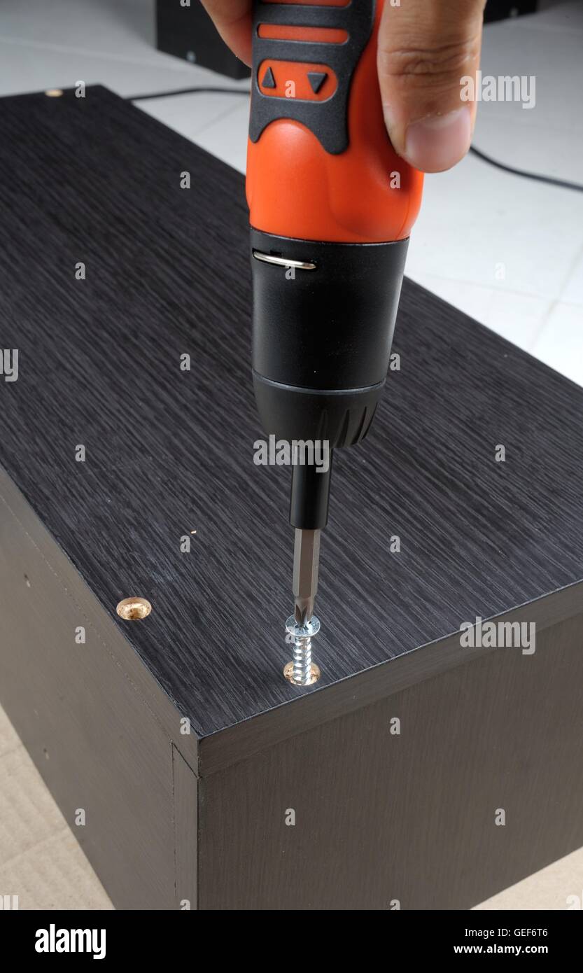 Le viti del lavoratore in un arredamento in legno con un cacciavite Foto Stock