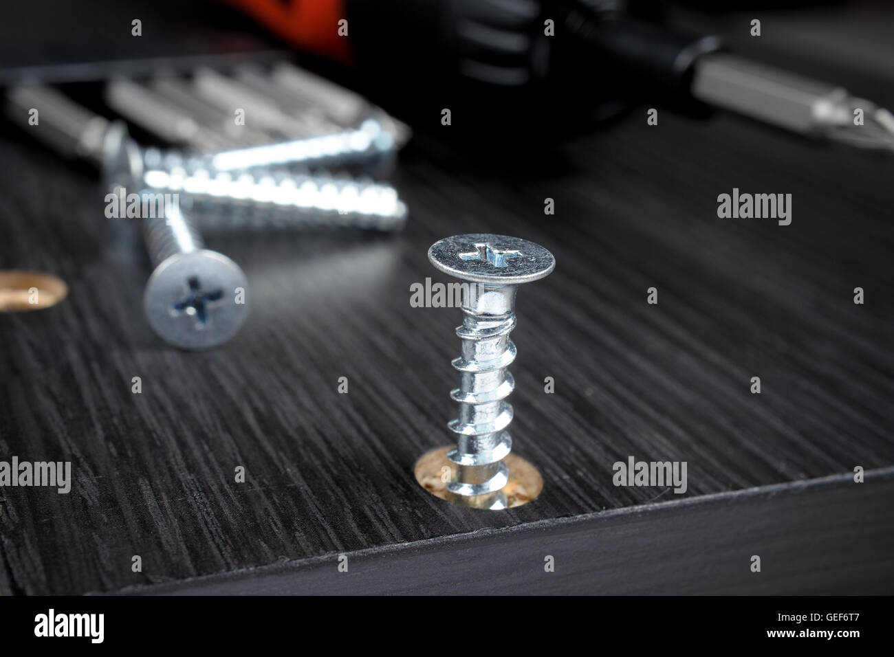 Le viti del lavoratore in un arredamento in legno con un cacciavite Foto Stock