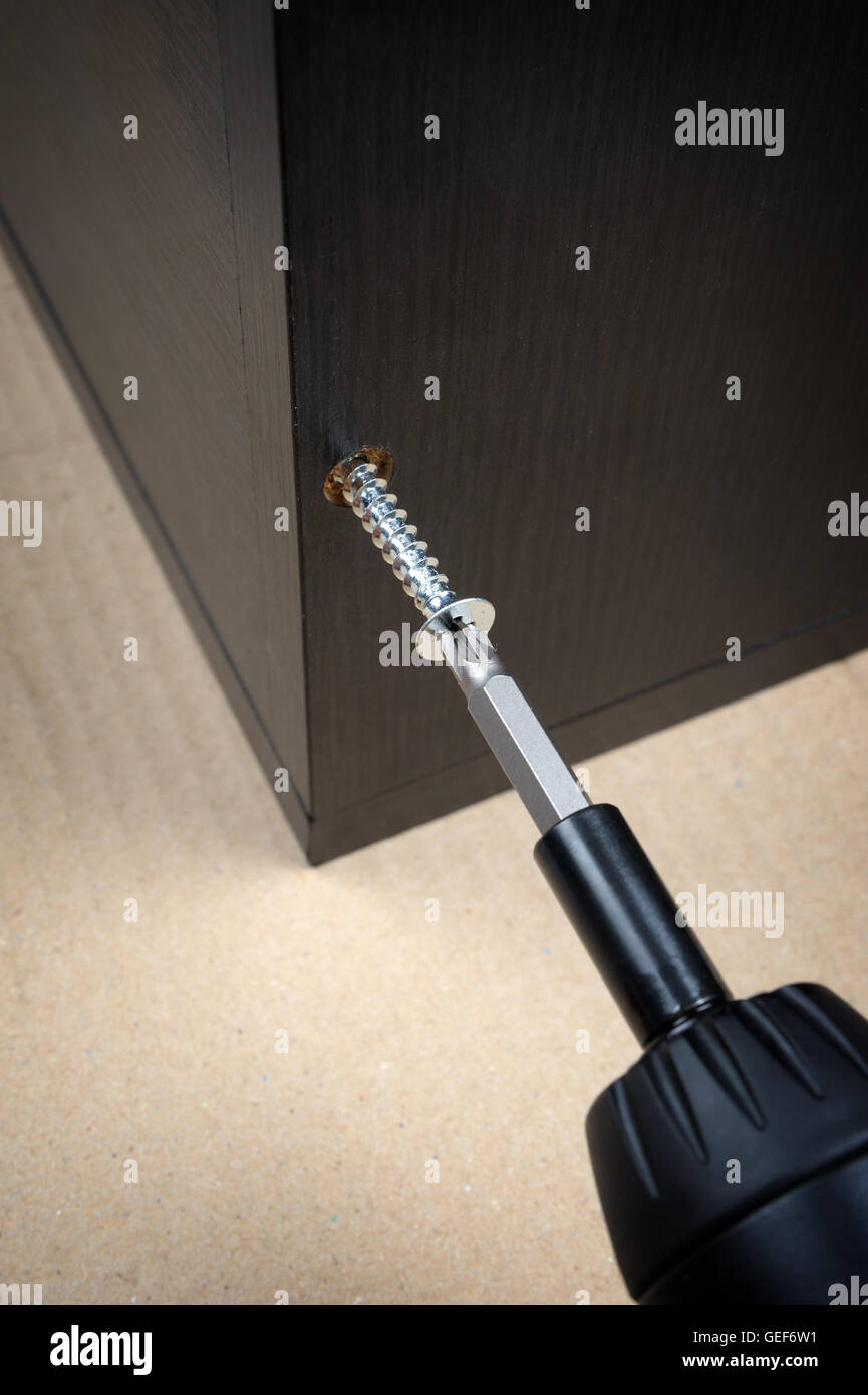 Le viti del lavoratore in un arredamento in legno con un cacciavite Foto Stock