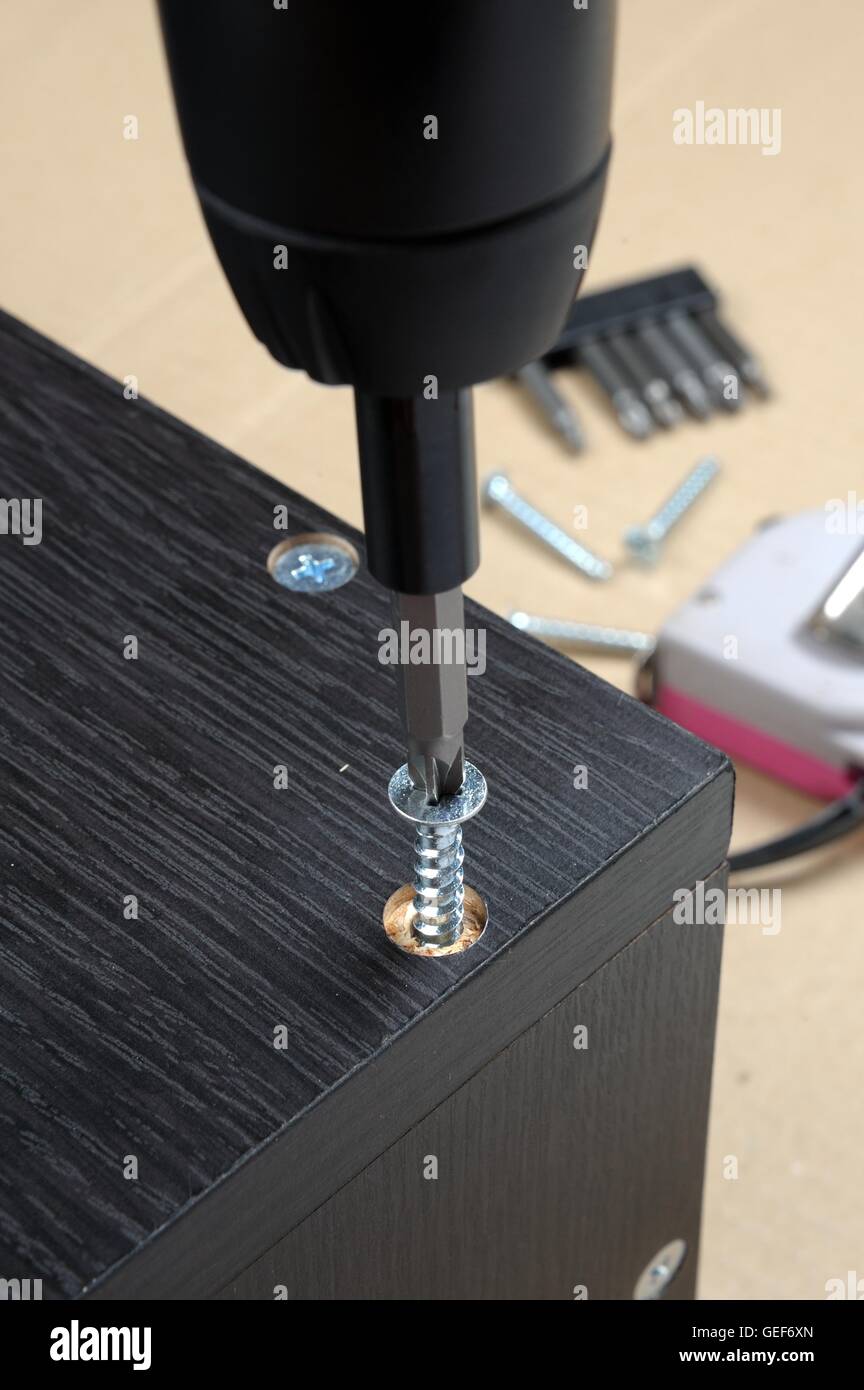 Le viti del lavoratore in un arredamento in legno con un cacciavite Foto Stock