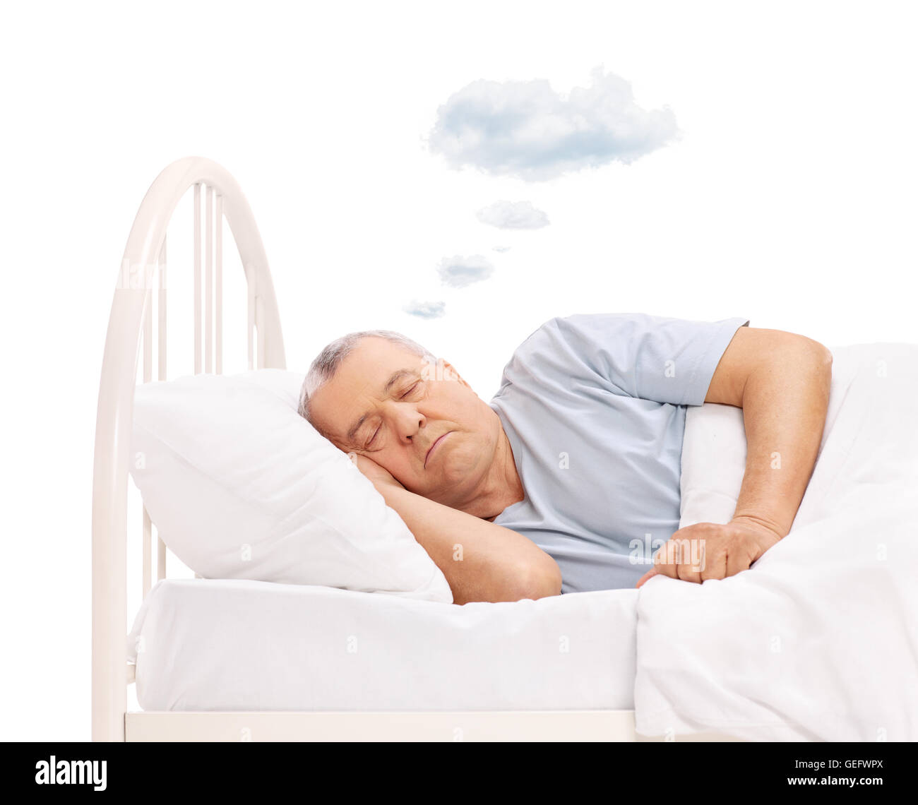 Uomo maturo di dormire su un letto e sognare con una nuvola sopra la sua testa isolata su sfondo bianco Foto Stock