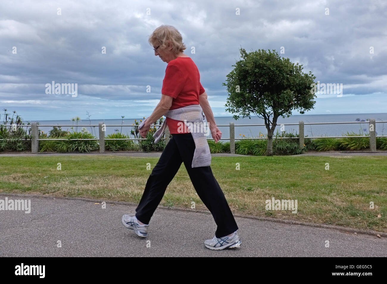 Donna che cammina lungo il lungomare di Falmouth, Regno Unito Foto Stock