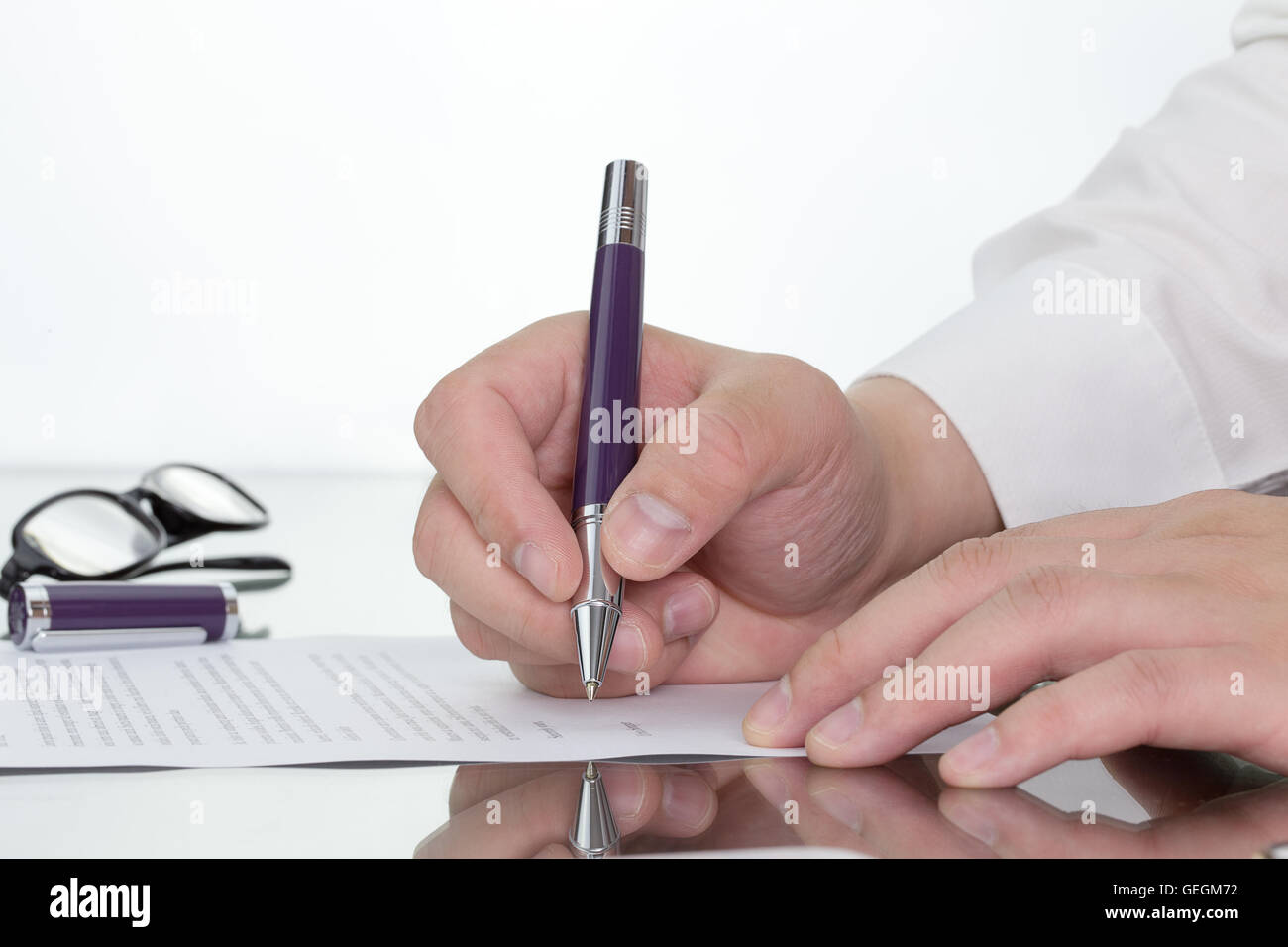 Imprenditore lavora sulla sua scrivania con la mano che tiene la penna di riflessione. Foto Stock