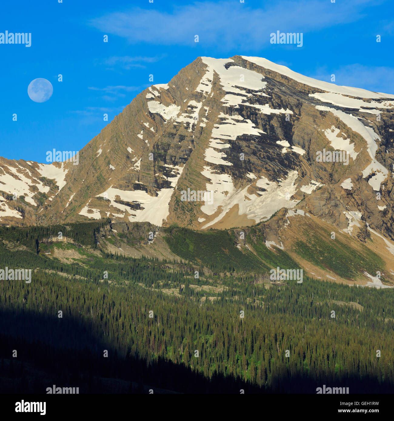 Impostazione luna dietro cieli picco nel parco nazionale di Glacier, montana Foto Stock
