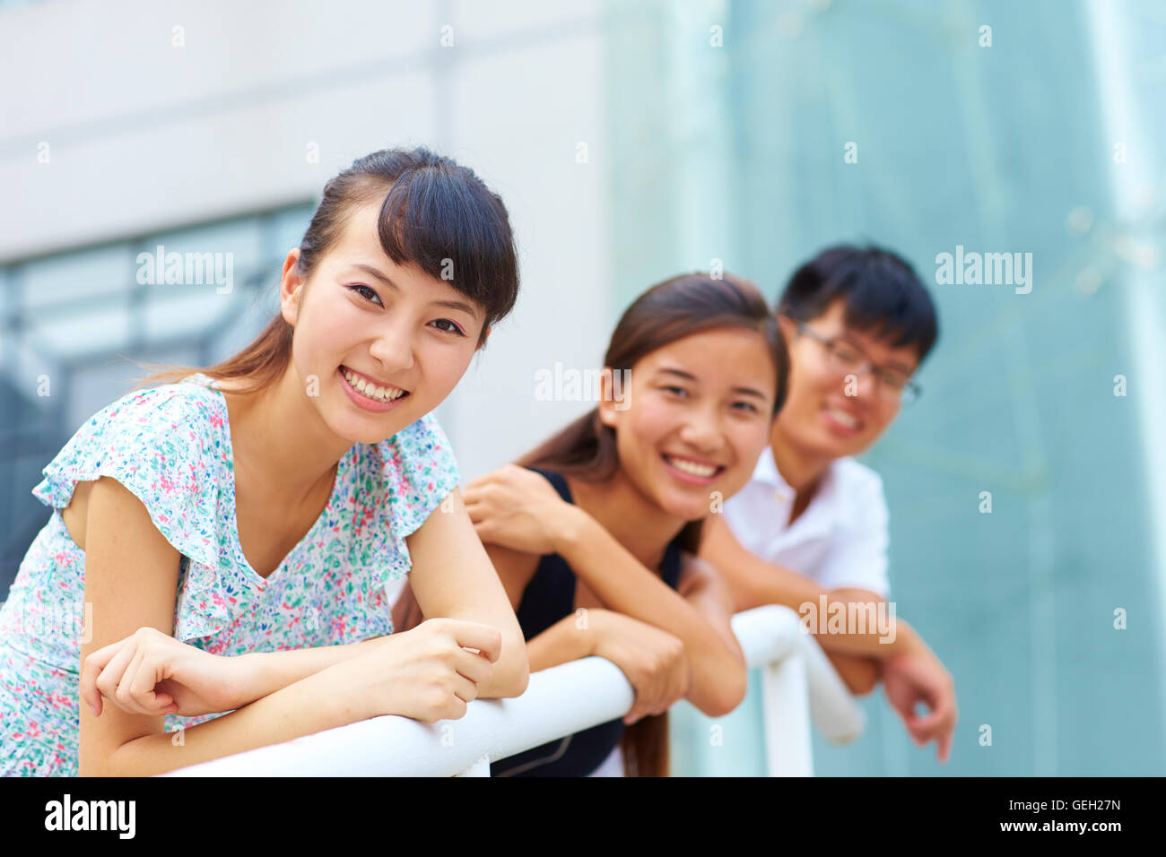 Tre giovani felici cinese o asiatica di studenti del college guardando il sorriso della fotocamera Foto Stock