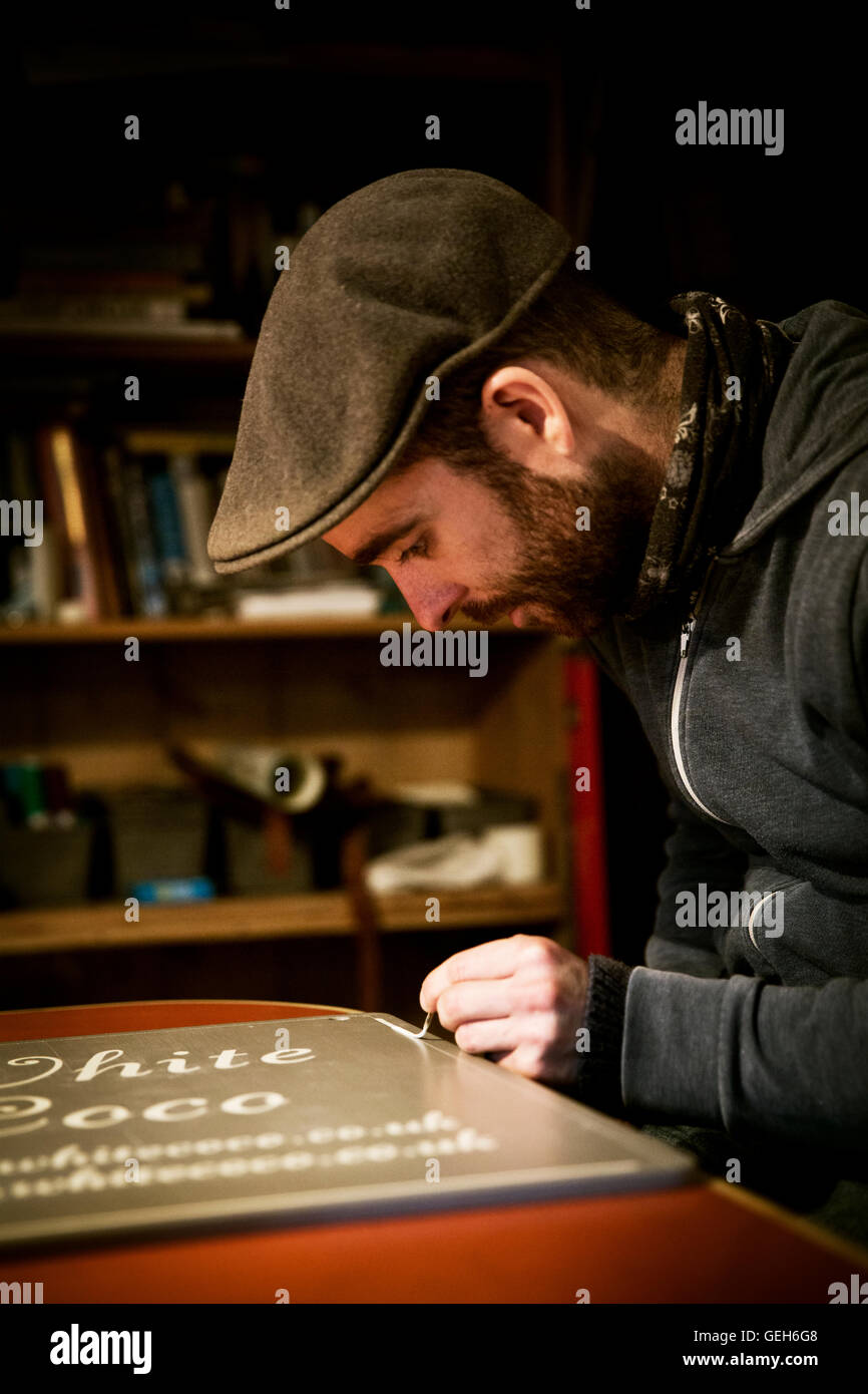 Un segno scrittore lavora con un carico verniciatura a pennello una linea freehand sul bordo di un segno. Foto Stock