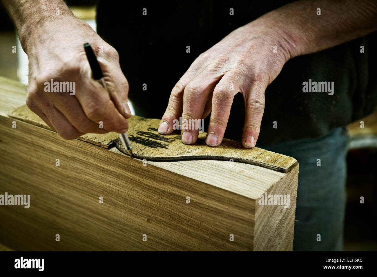 Un uomo che lavora in un mobilio maker's workshop disegno intorno a una forma di legno. Foto Stock