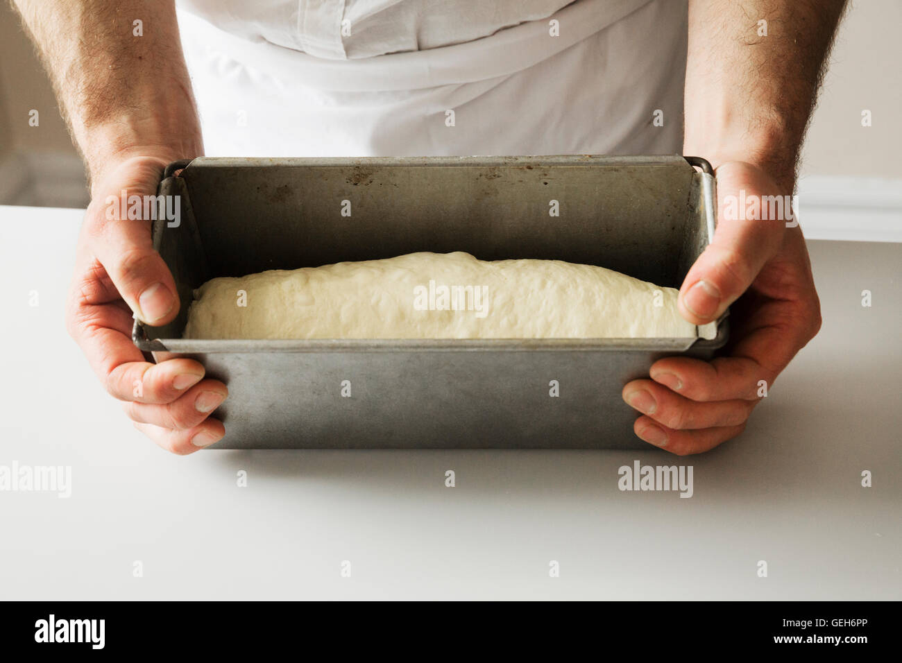 Close up di un fornaio tenendo una teglia riempita con pasta di pane. Foto Stock