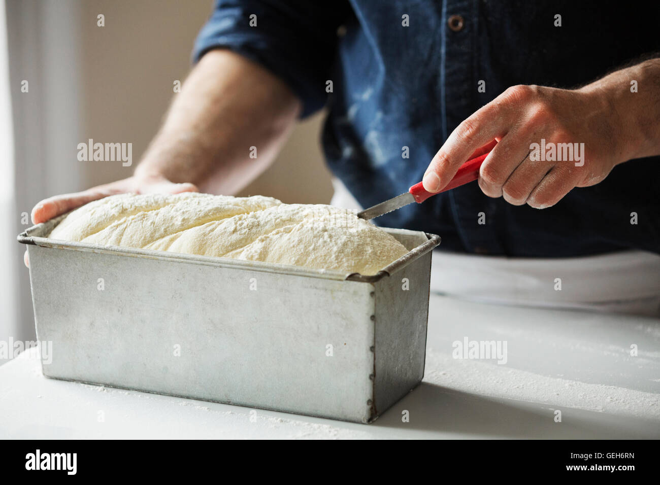 Close up di un fornaio il taglio di pasta di pane in una teglia da forno. Foto Stock