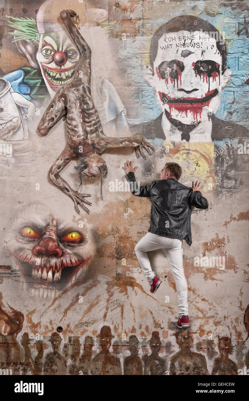 L uomo si arrampica su una parete piena di graffiti Foto Stock