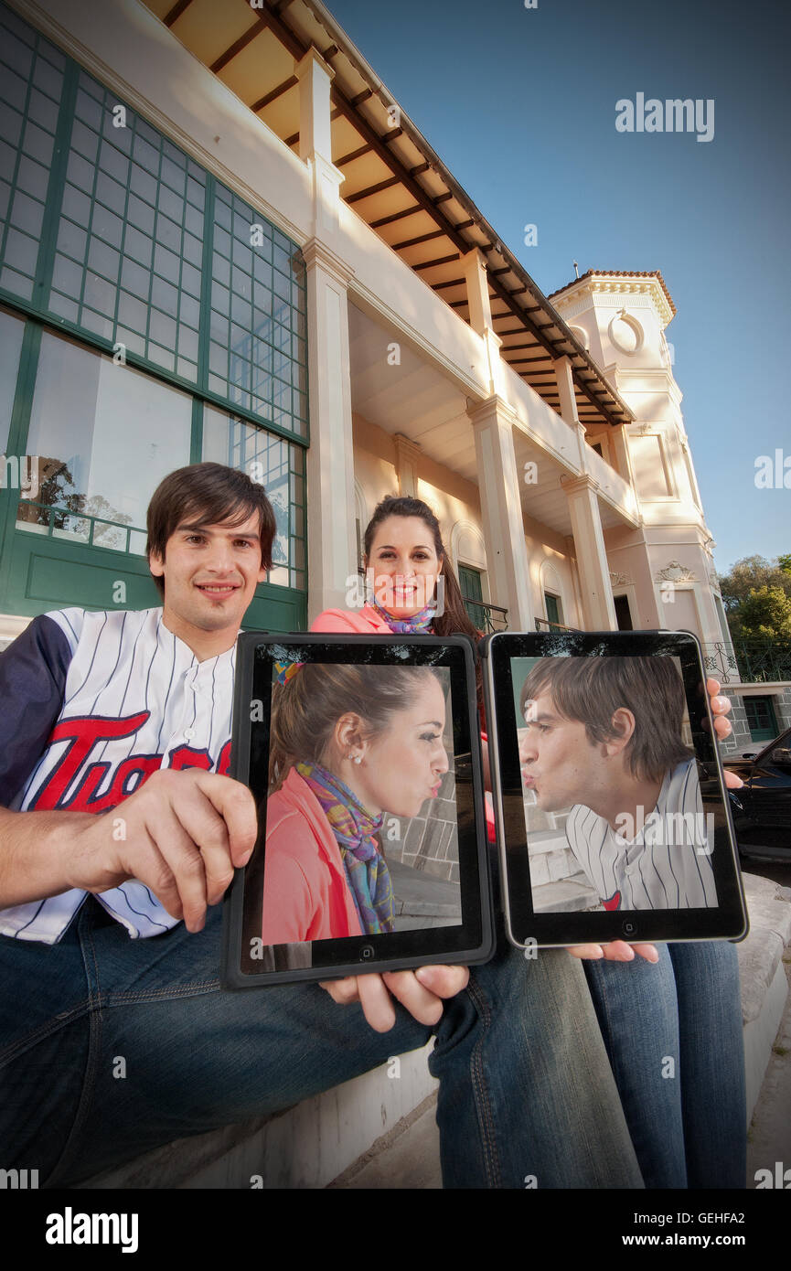 Matura mostrano il loro compresse affacciati con le immagini dei loro baciare Foto Stock