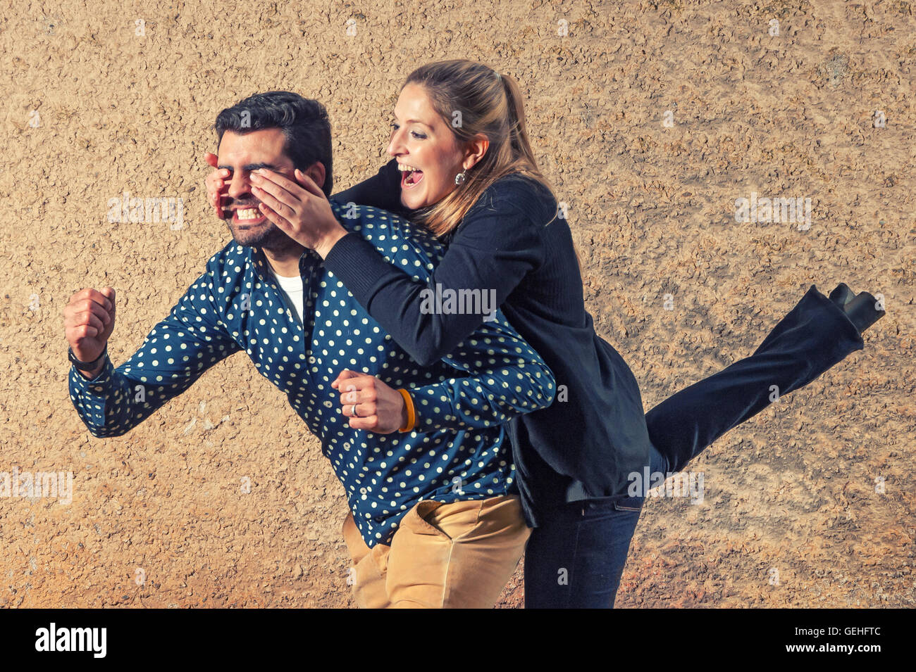 Ragazza sorprese il suo ragazzo da dietro che copre la sua gli occhi Foto Stock