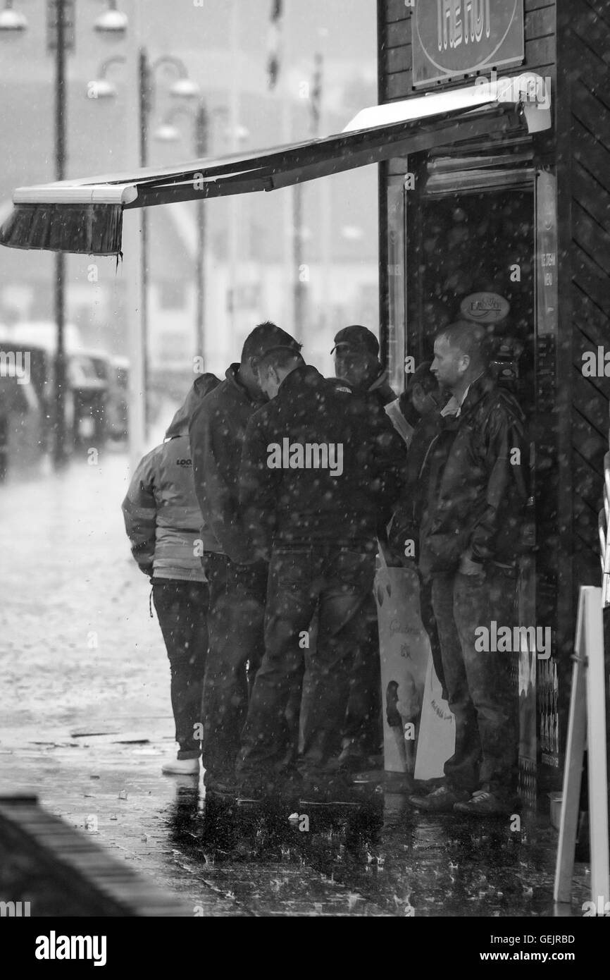 Un gruppo di persone si ripara dalla pioggia sotto un baldacchino Foto Stock