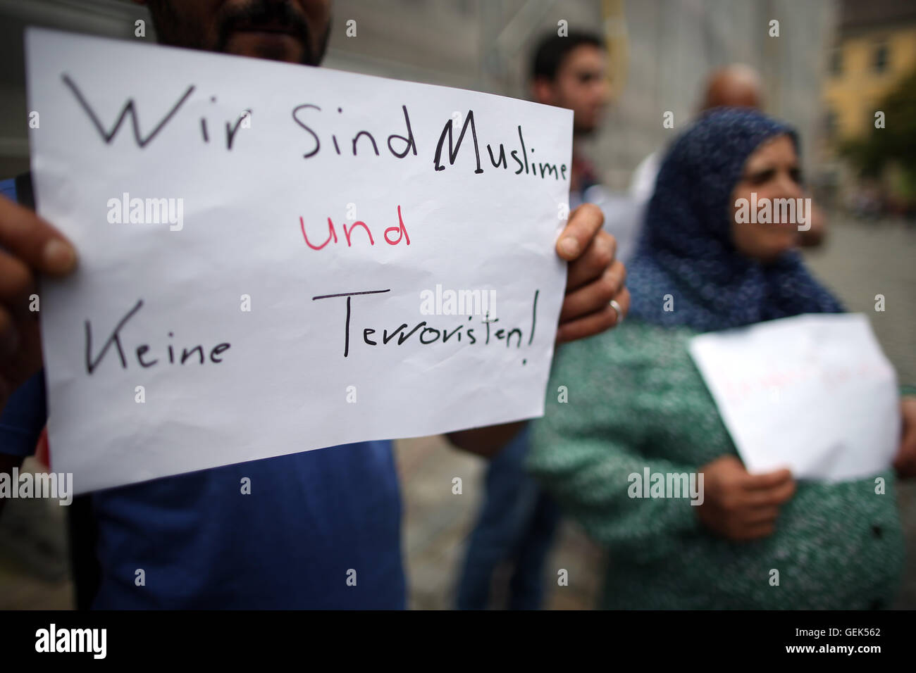 Ansbach, Germania. 26 Luglio, 2016. Rifugiati dalla Siria stare vicino al sito di attacco e tenere premuto su un cartello con la scritta "siamo musulmani e non terroristi" in Ansbach, Germania, 26 luglio 2016. 15 persone sono rimaste ferite in un islamista sospetti motivati attaccare il 24 luglio 2016. Il sospettato colpevole, un 27-anno-vecchio rifugiato dalla Siria, è stato ucciso nell'esplosione. Foto: DANIEL KARMANN/dpa/Alamy Live News Foto Stock