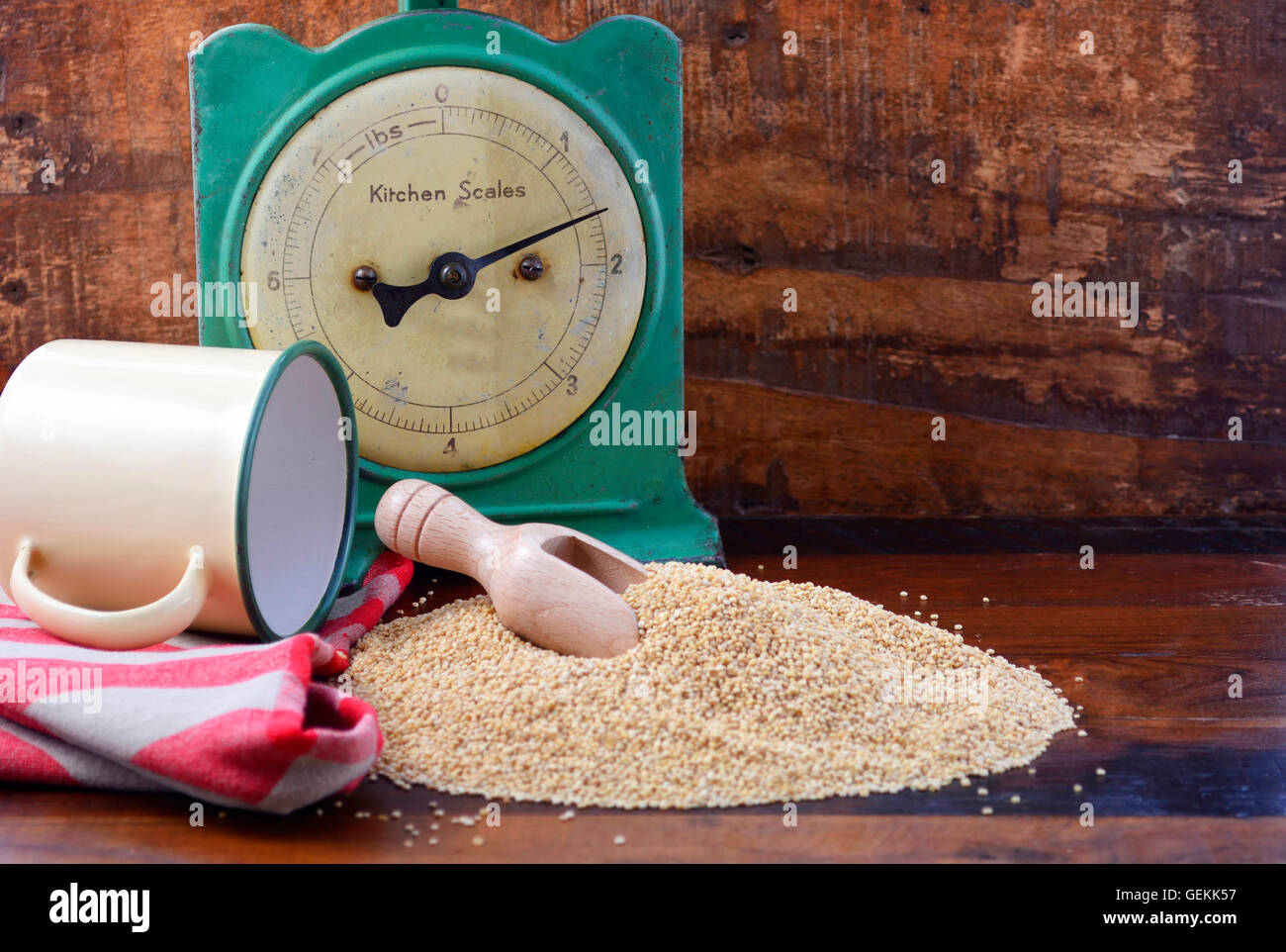 Pila di quinoa granella con la paletta di legno con vintage bilancia da cucina e tin cup coppa sul legno scuro sfondo, con copia spazio. Foto Stock