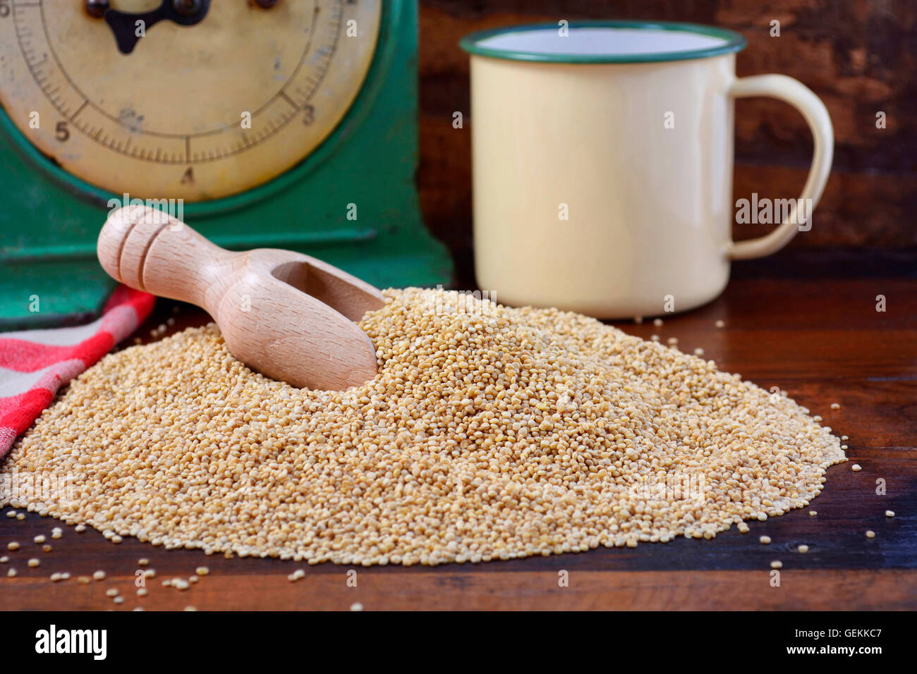 Pila di quinoa granella con la paletta di legno con vintage bilancia da cucina e tin cup coppa sul legno scuro sfondo, closeup. Foto Stock