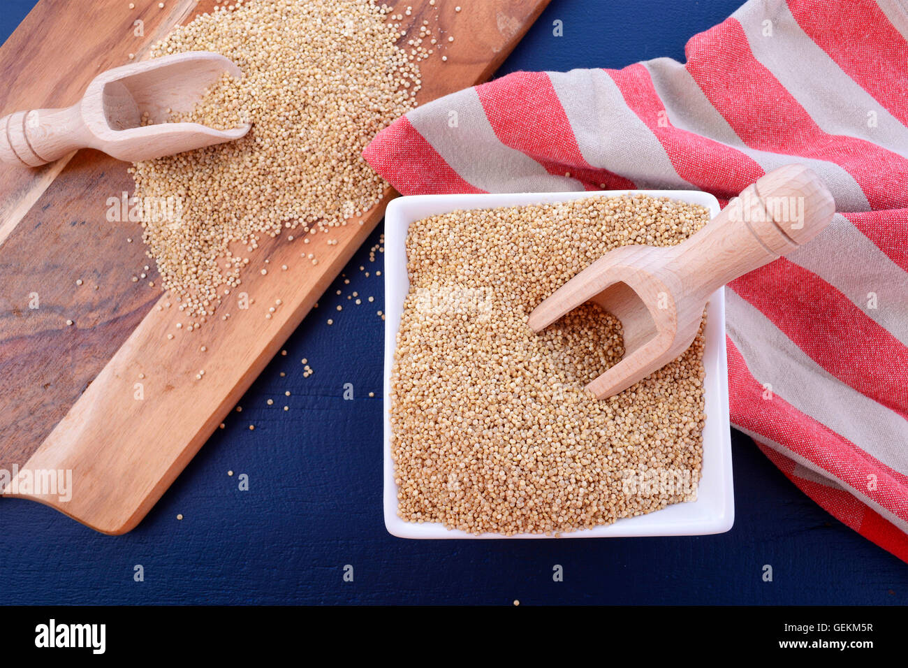 Grano bianco quinoa con palline di legno e tagliere in blu scuro dello sfondo di legno. Foto Stock