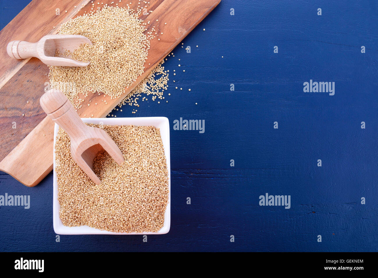 Grano bianco quinoa con palline di legno e tagliere in blu scuro dello sfondo di legno, con copia spazio. Foto Stock