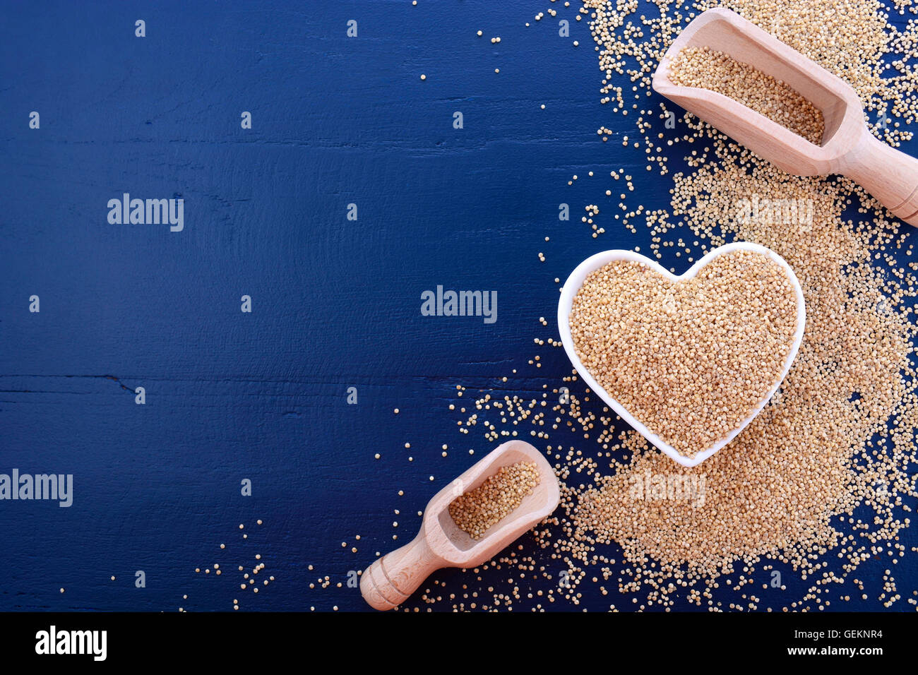 Io amo la quinoa concetto con grano bianco quinoa in bianco a forma di cuore sulla tazza di un blu scuro dello sfondo di legno. Foto Stock