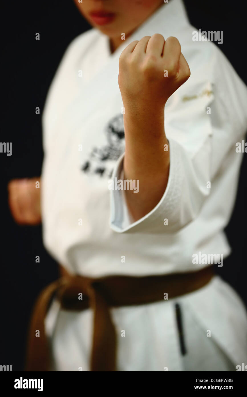 Ragazzo giapponese nel karate uniforme su sfondo nero Foto Stock