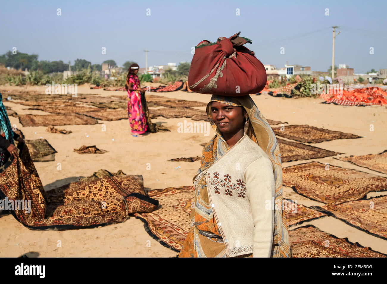 Sanganer, India - gennaio 2013. Un sorridente donna indiana in un campo completo di blocco di tessuto stampato di essiccazione al sole. Foto Stock