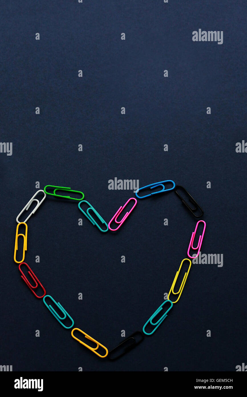 Multi colore clip di carta a forma di cuore su sfondo semplice Foto Stock