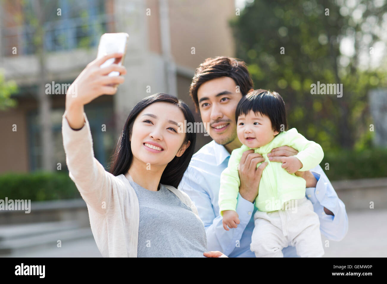 Felice giovane famiglia cinese tenendo autoritratto con uno smart phone Foto Stock