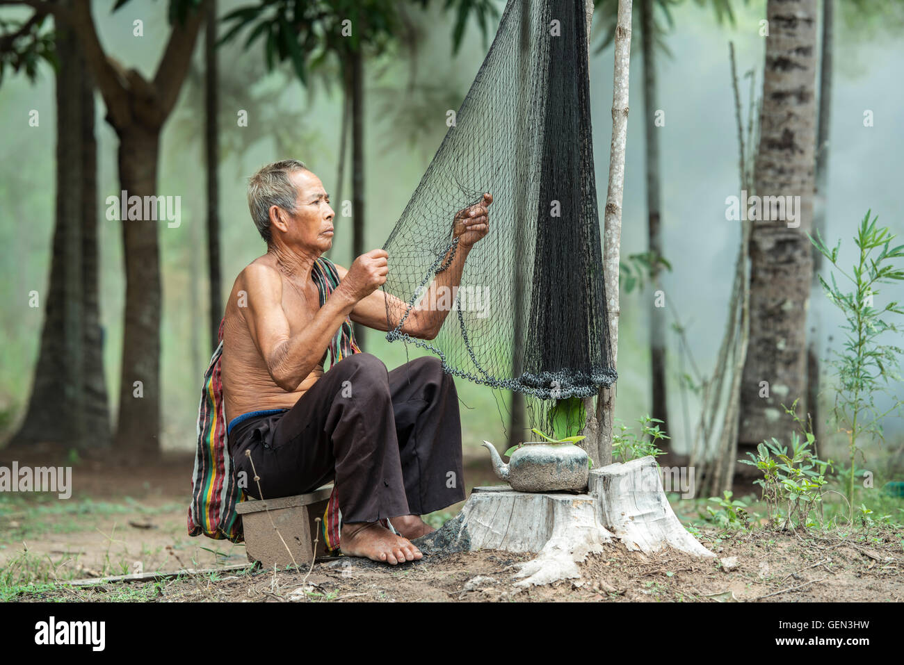 Uomo asiatico al lavoro e ispezionando le sue reti,verifica del lavoro di attrezzatura da pesca. Foto Stock