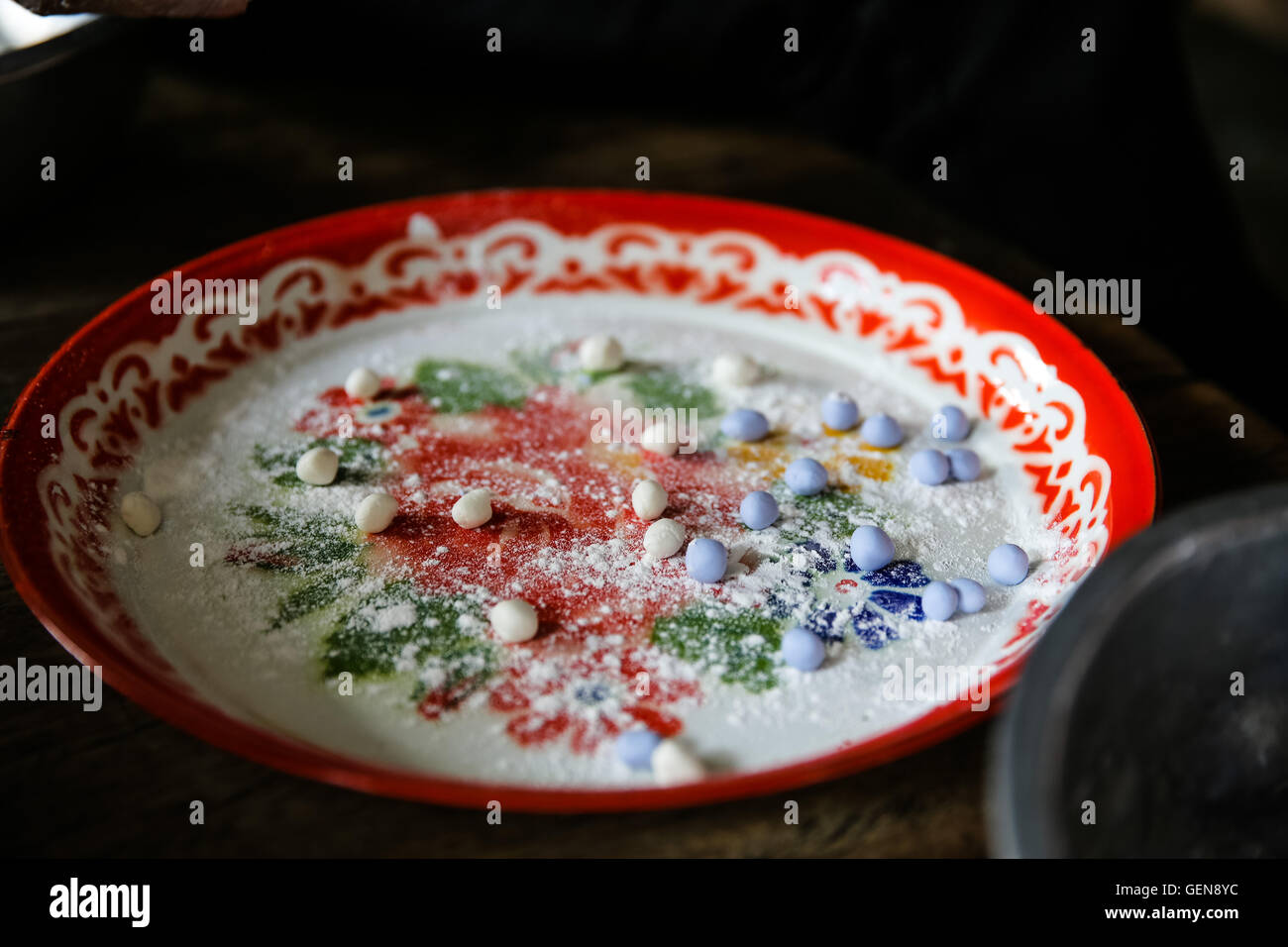 Appena stampata blu viola e bianco palla di impasto dessert su un rivestimento rosso che serve il vassoio con cosparso di farina Foto Stock