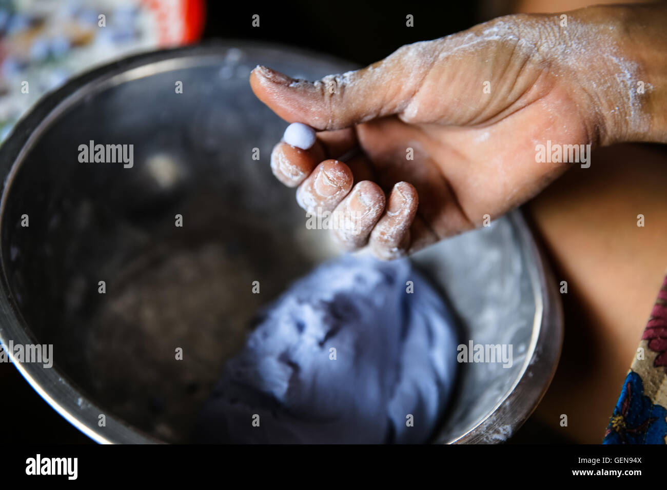 Rivolti verso l'alto lo stampaggio a mano viola pasta blu metallo caramella della vaschetta di miscelazione di pasta di contenimento e spostandolo su un vassoio colorato tan da polso Foto Stock