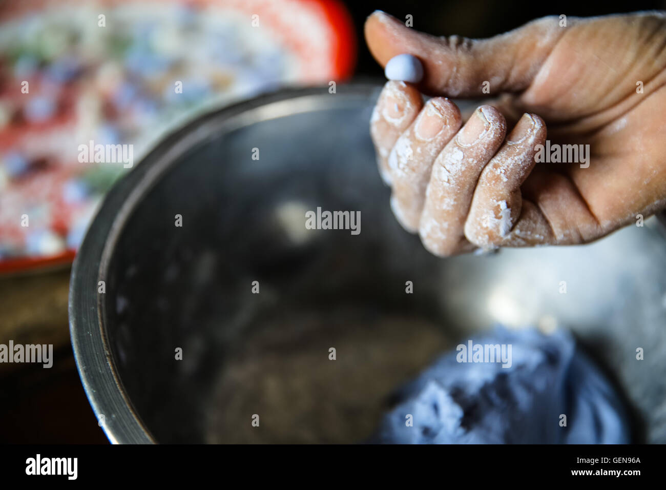 Rivolta verso l'alto mano con dita stampaggio blu porpora caramella di pasta recipiente metallico azienda impasto e spostarlo su un vassoio colorato Foto Stock