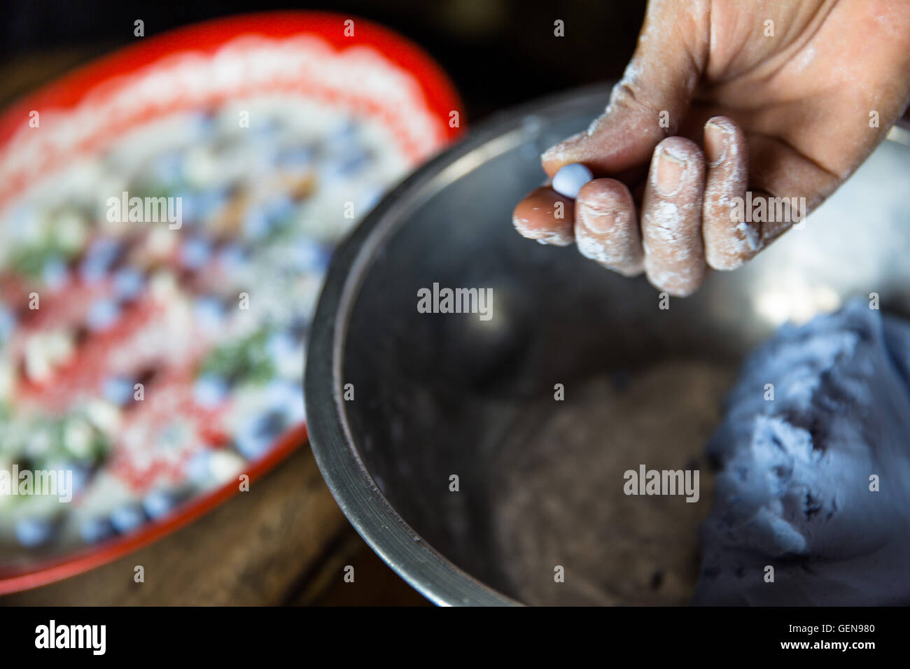 Rivolta verso l'alto mano con dita stampaggio blu porpora caramella di pasta recipiente metallico azienda impasto e spostarlo su un vassoio colorato Foto Stock