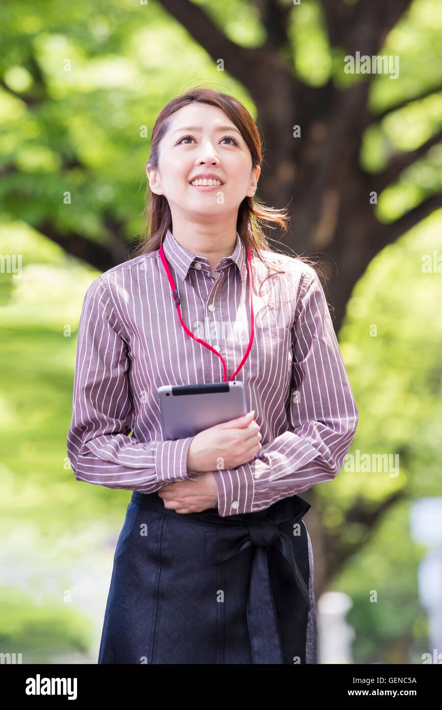 Business donna camminando lungo con strada alberata Foto Stock