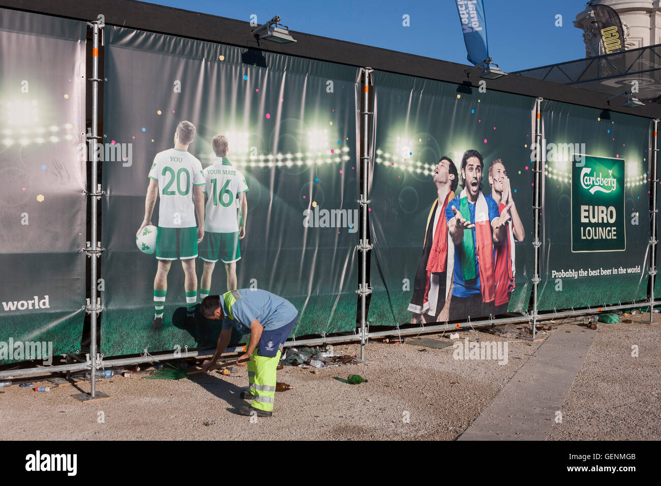 Un lavoratore cittadino spazza figliata da sotto la pubblicità di Carlsberg a Lisbona la Praca do Commercio la mattina dopo il Portogallo vittoria Foto Stock