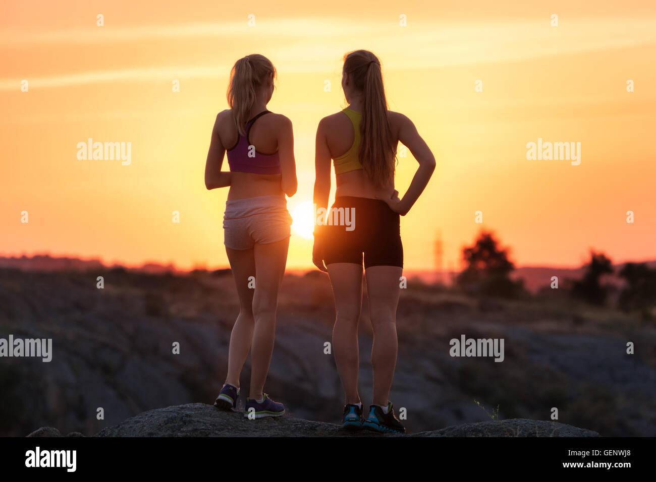 Bellissimo paesaggio con silhouette di giovani ragazze sportivo al tramonto sulla montagna in estate. Donne Fitness riposo dopo lo sport Foto Stock