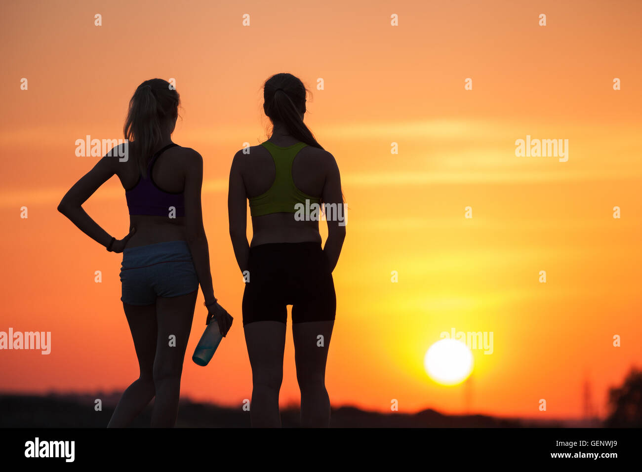 Bellissimo paesaggio con silhouette di giovani ragazze sportivo al tramonto sulla montagna in estate. Donne Fitness riposo dopo lo sport Foto Stock